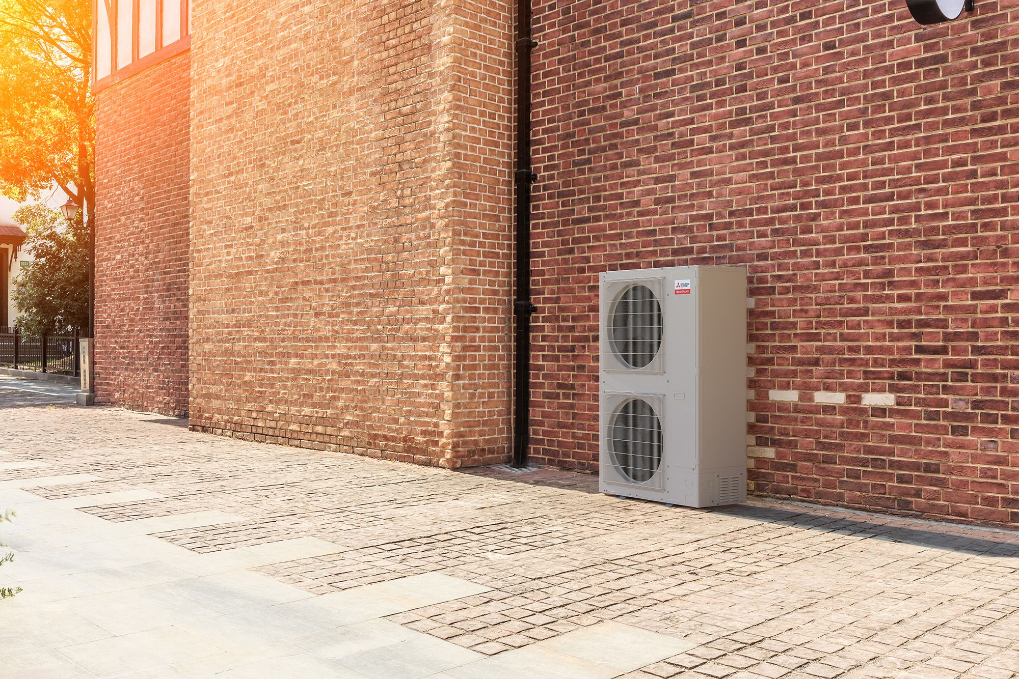 Mitsubishi Electric smart multi outdoor heat pump unit next to brick wall of light commercial building